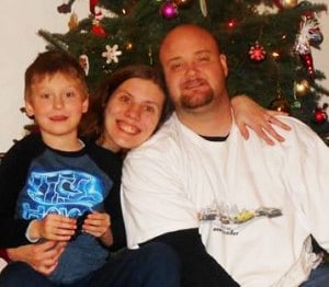 A photo of the roberts family, mom, dad and son in front of a Christmas tree